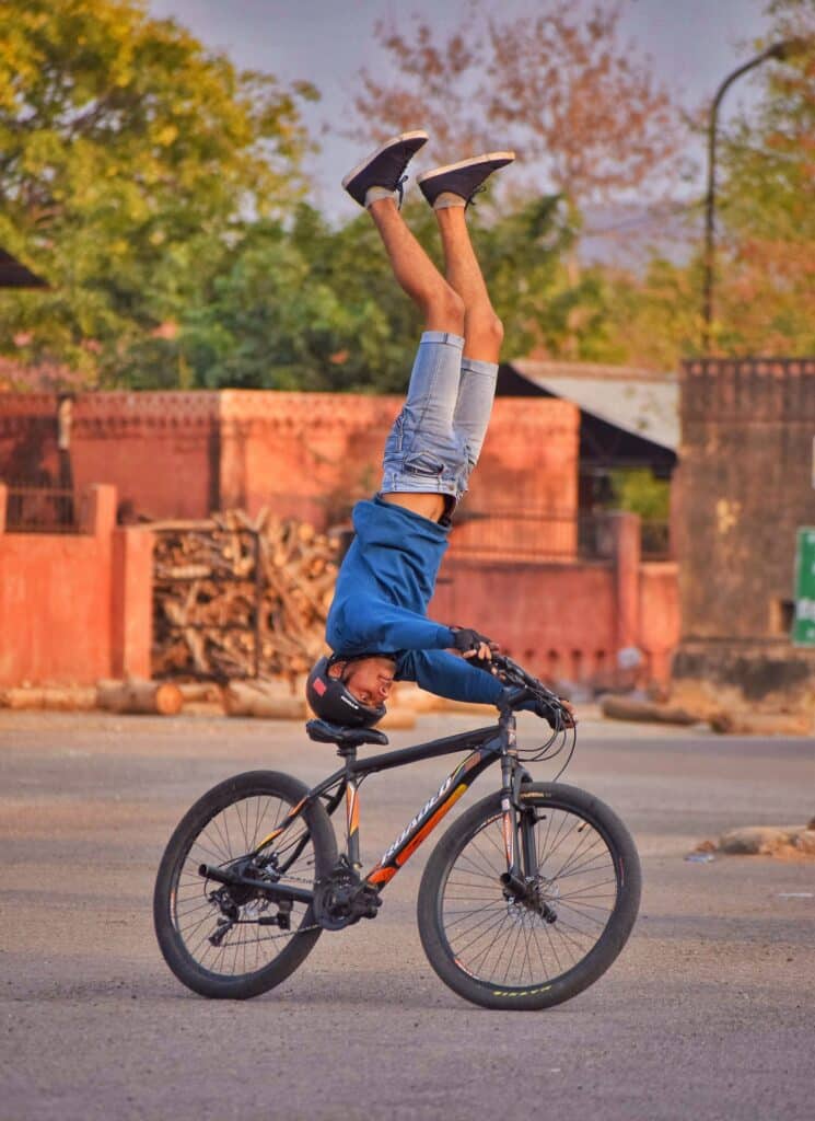 Man riding a bike doing a headstand on the seat. Photo courtesy of Lakshya Mudgal on Pexels