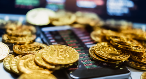 A stash of golden Bitcoins surrounding and on the face of a cellphone showing asset prices