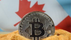 A physical Bitcoin standing vertically in front of a Canadian flag with the maple leaf angled up and to the right