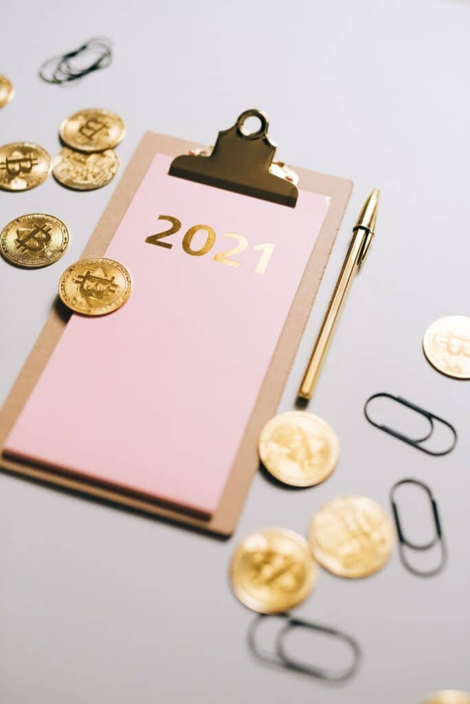 A notepad with a pen and several bitcoins strewn around. Photo courtesy of Olya Kobruseva at Pexels