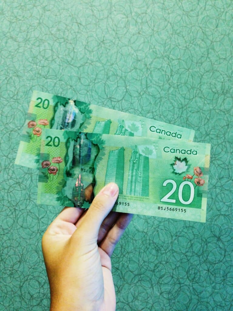 A woman’s left hand holding 2 Canadian $20 bills. Photo courtesy of Michelle Spollen