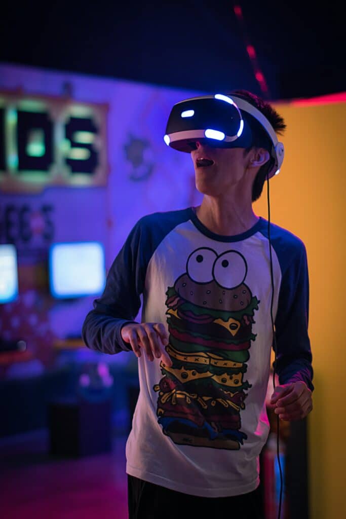 Young man with open mouth, wearing VR glasses and a cookie monster shirt. Photo courtesy of Uriel Soberanes on Upsplash