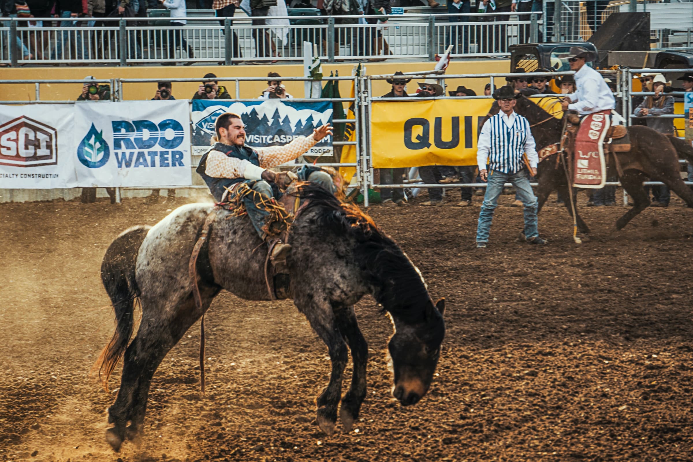 Cowboy riding a bronc in a competition and holding on tight. Photo courtesy of Jordan Heinrichs