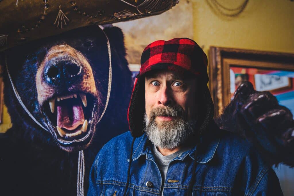 Frightened man in a hunting cap with an angry stuffed bear over his shoulder. Image courtesy of Brett Sayles at Pexels